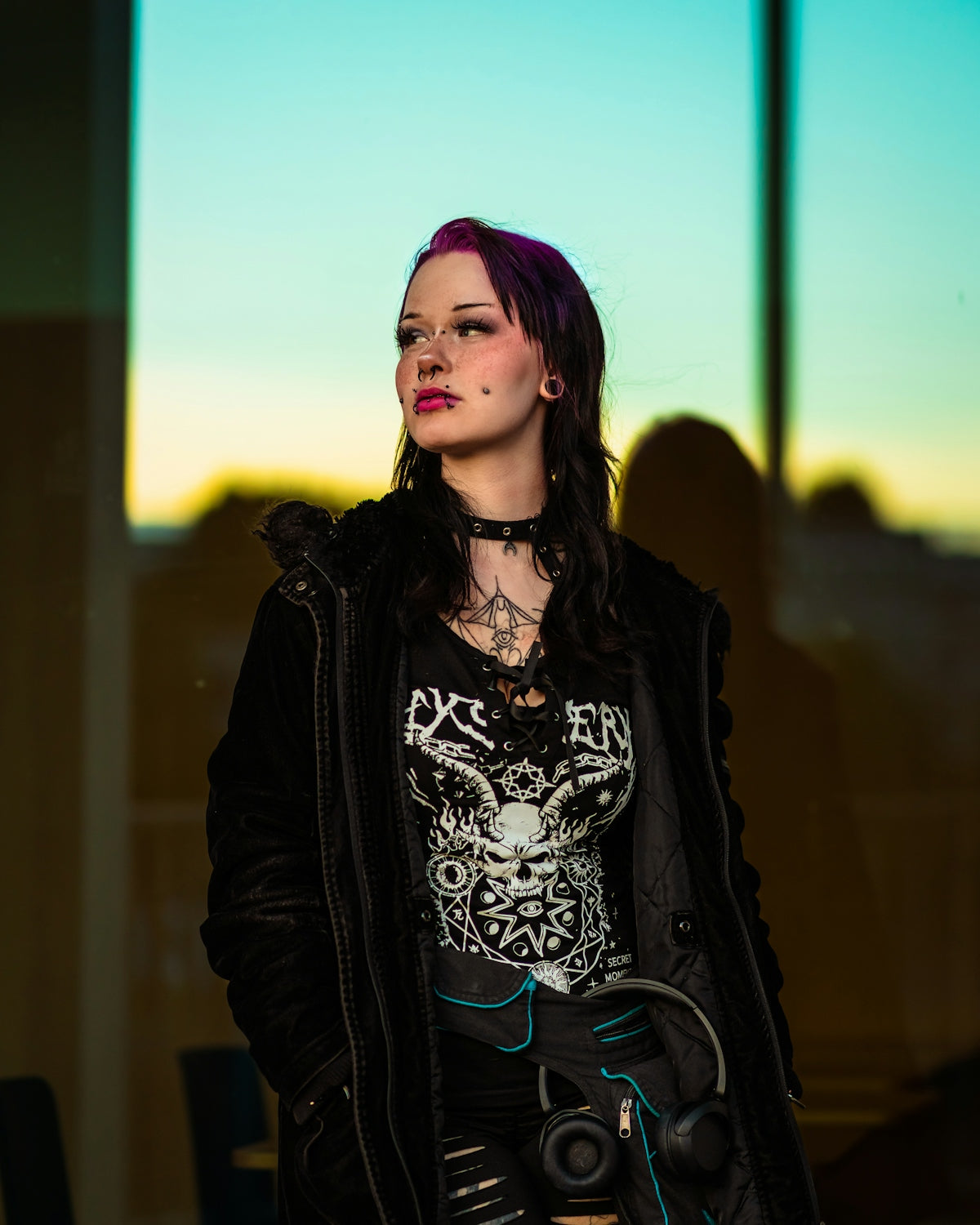 A woman with purple hair and alternative clothing looks away