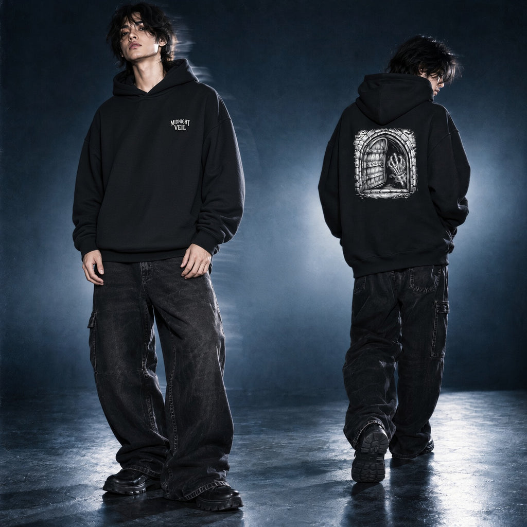A model is shown from the front and back wearing a black pullover hoodie with graphic prints. The front view shows a small white chest graphic, while the back view shows a large white gothic-style graphic of a hand inside a window frame.