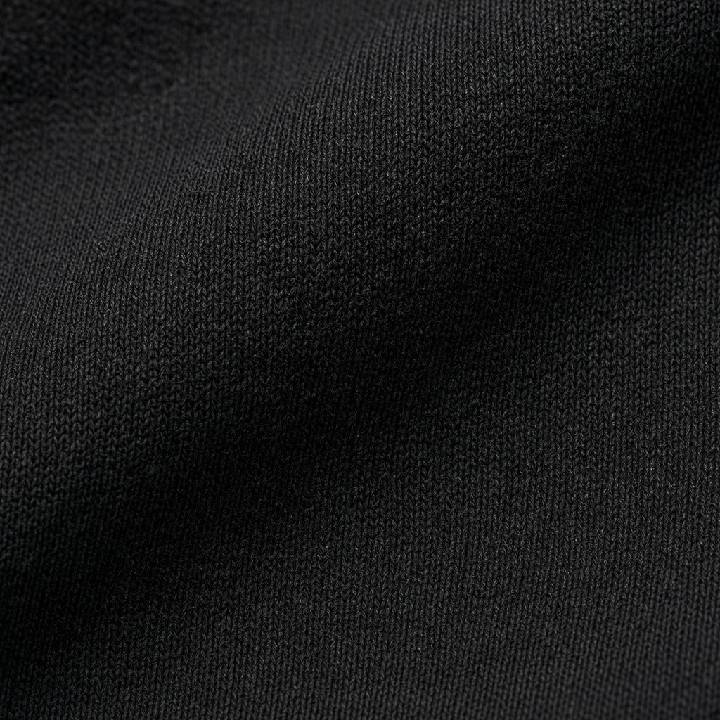 Macro close-up photography of the premium 7oz 237GSM combed ring-spun cotton fabric texture on the Midnight Veil Obsidian Black streetwear box tee.
