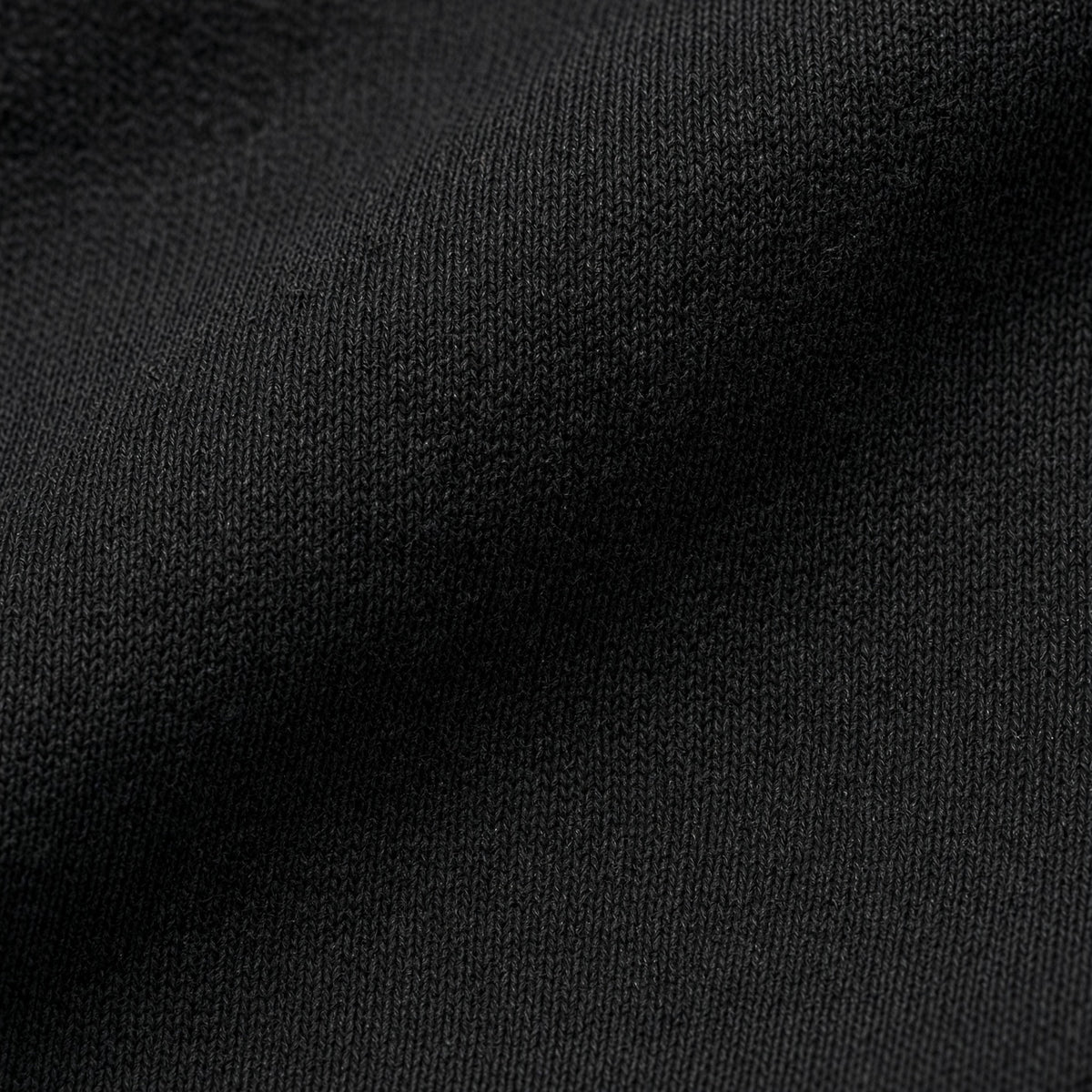 Macro close-up photography of the premium 7oz 237GSM combed ring-spun cotton fabric texture on the Midnight Veil Obsidian Black streetwear box tee.
