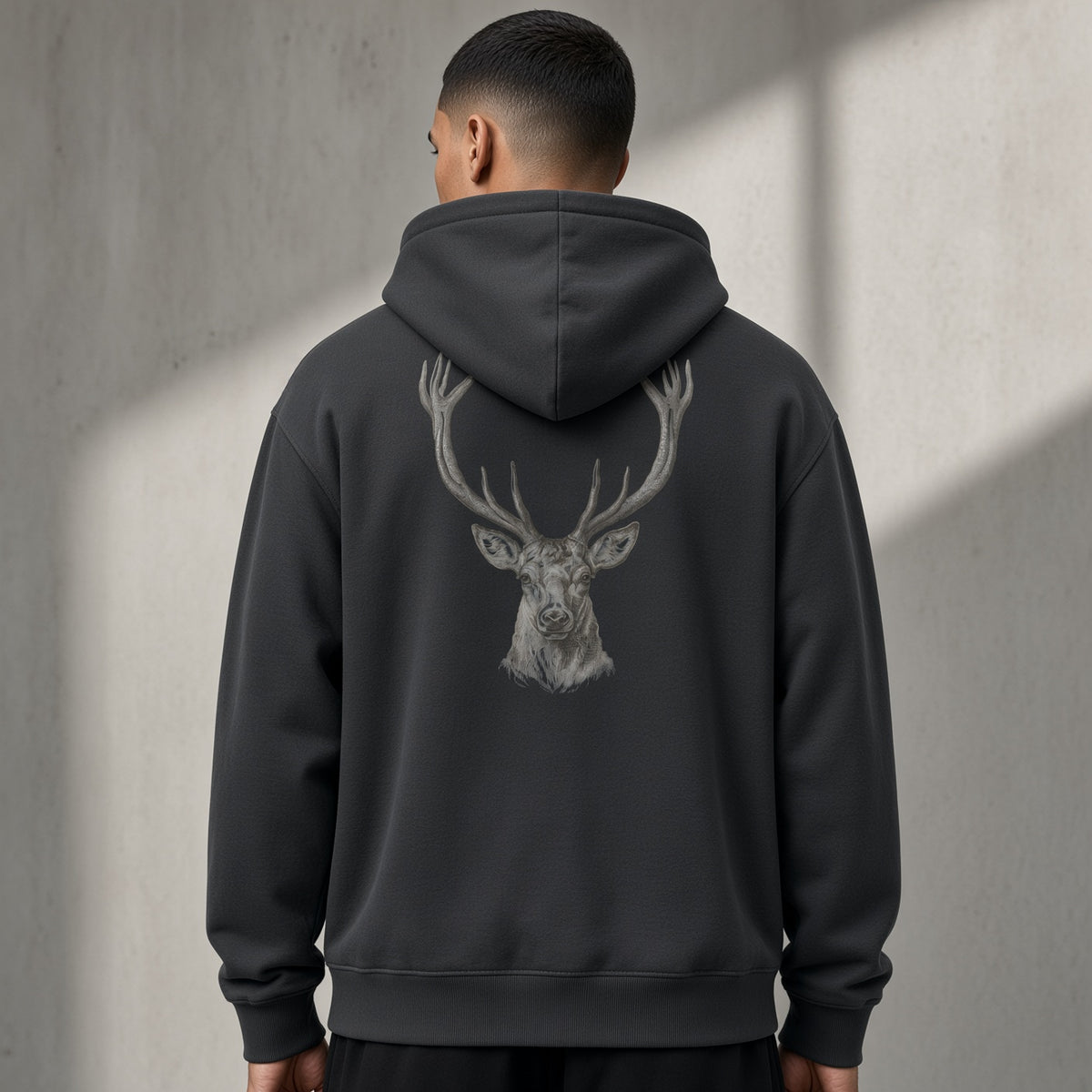 Back of a black heavyweight hoodie with a grey stag head print, worn oversized